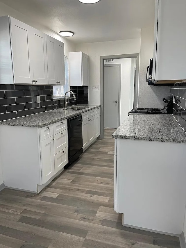 kitchen featuring dishwasher, sink, hardwood / wood-style flooring, white cabinets, and range