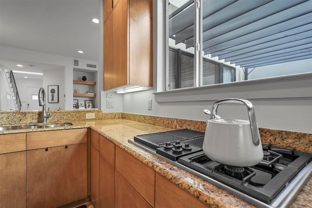 kitchen with light stone counters, sink, and stainless steel gas cooktop