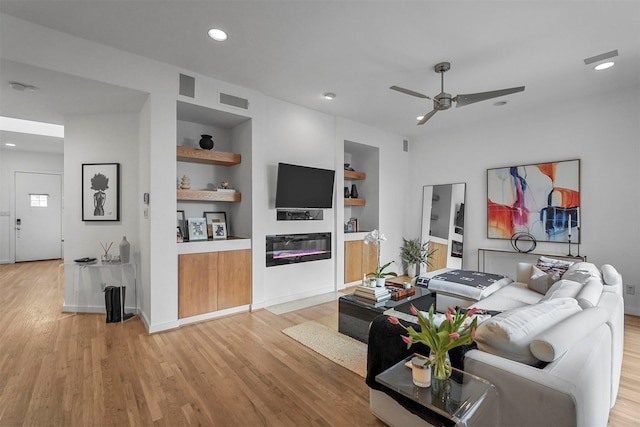 living room with ceiling fan, built in features, and light hardwood / wood-style floors