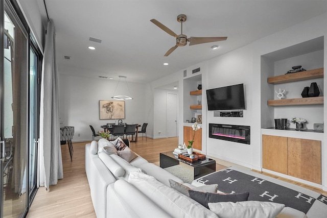 living room featuring light hardwood / wood-style flooring, built in features, and ceiling fan