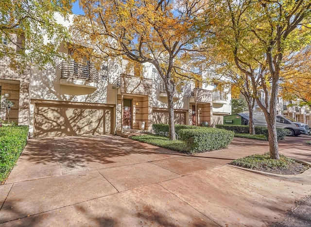 multi unit property featuring driveway, an attached garage, and stucco siding