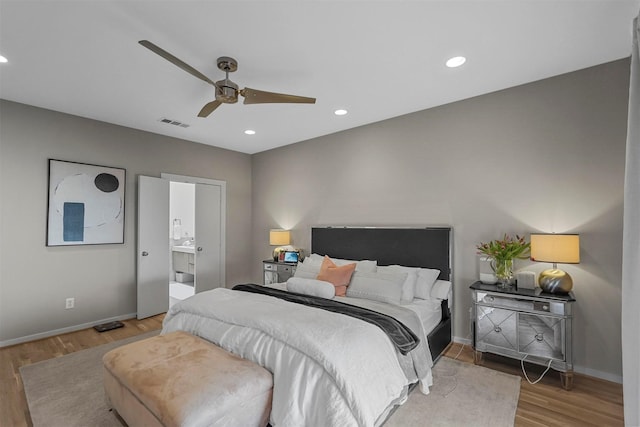 bedroom with ceiling fan, light wood-type flooring, and connected bathroom