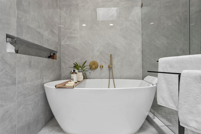 bathroom featuring tile walls and a tub