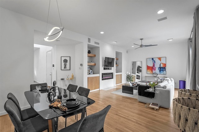 dining room with ceiling fan, built in features, and light hardwood / wood-style floors