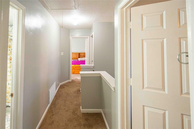 corridor with a textured ceiling and carpet flooring