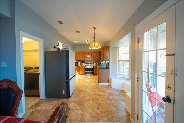 kitchen featuring black refrigerator, double oven range, washing machine and dryer, and pendant lighting