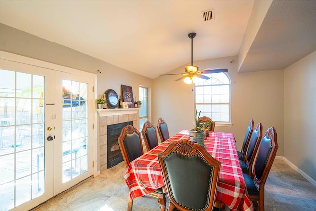 dining area with french doors, ceiling fan, lofted ceiling, and a tile fireplace