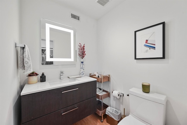 bathroom with hardwood / wood-style floors, vanity, and toilet