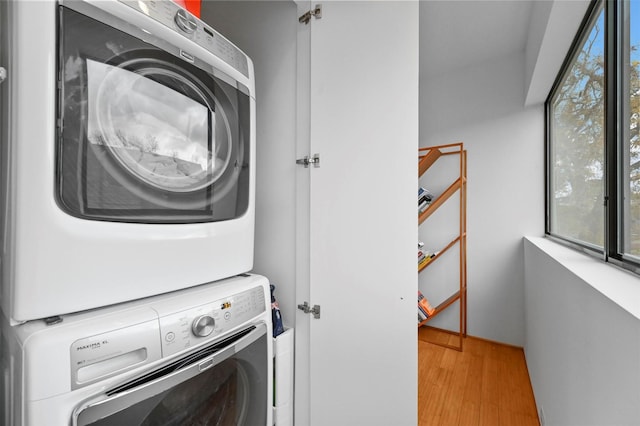 clothes washing area with light hardwood / wood-style floors and stacked washer and clothes dryer