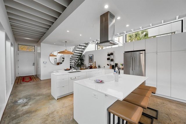 kitchen with white cabinets, a kitchen breakfast bar, island exhaust hood, and high quality fridge