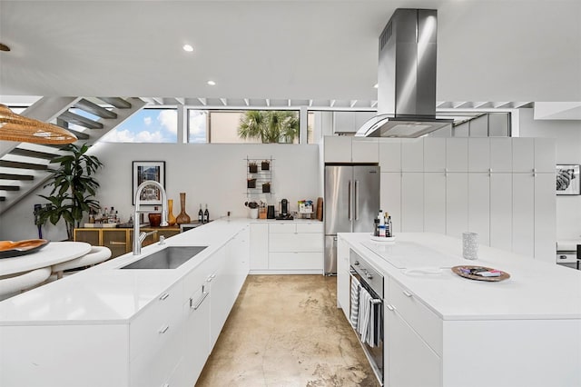 kitchen with high end fridge, exhaust hood, sink, white cabinets, and a large island