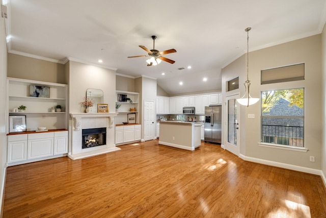 unfurnished living room featuring light wood-style flooring, recessed lighting, a fireplace, a ceiling fan, and crown molding