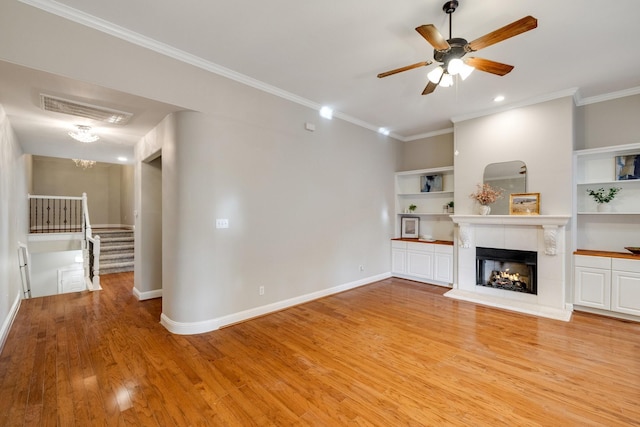 unfurnished living room with a fireplace, wood finished floors, visible vents, baseboards, and crown molding