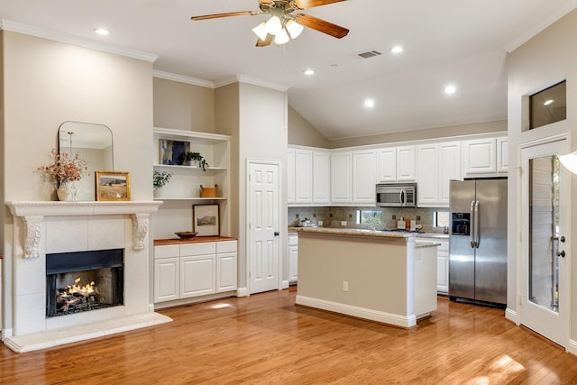 kitchen with stainless steel appliances, a fireplace, visible vents, and white cabinetry