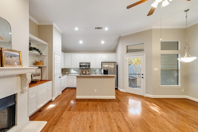 kitchen with stainless steel appliances, crown molding, white cabinetry, open shelves, and a high end fireplace