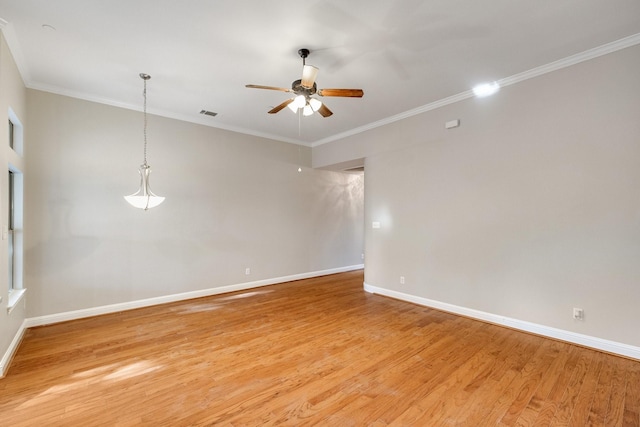 spare room with ceiling fan, visible vents, baseboards, light wood-type flooring, and crown molding