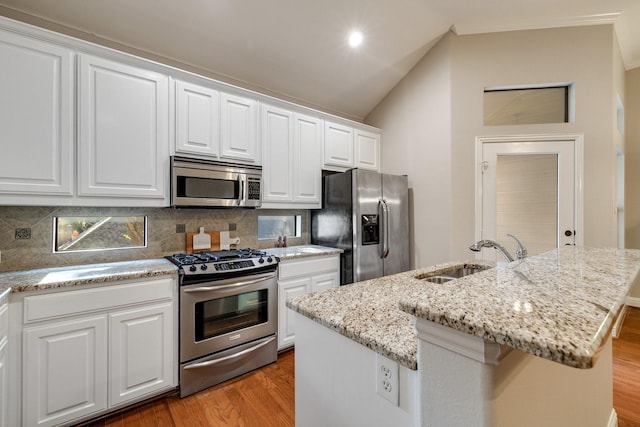 kitchen with lofted ceiling, a center island with sink, sink, wood-type flooring, and stainless steel appliances