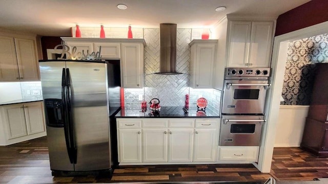 kitchen featuring backsplash, dark wood-type flooring, wall chimney range hood, and appliances with stainless steel finishes