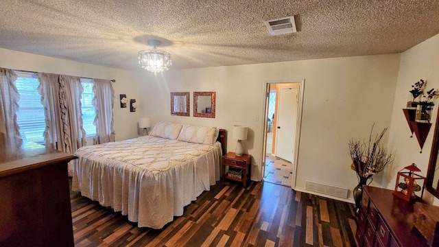 bedroom with a textured ceiling, dark wood-type flooring, and a notable chandelier