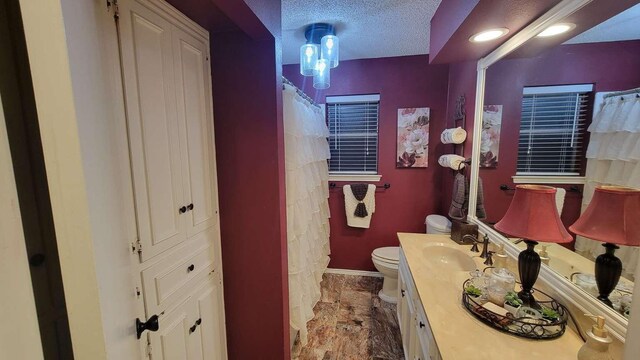 bathroom featuring a textured ceiling, vanity, and toilet