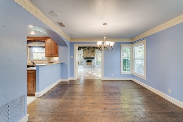 unfurnished dining area featuring dark hardwood / wood-style floors, ornamental molding, and an inviting chandelier