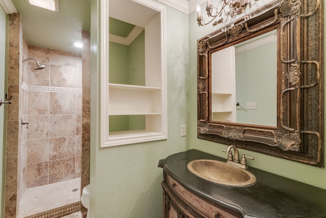 bathroom with a tile shower, crown molding, vanity, and toilet