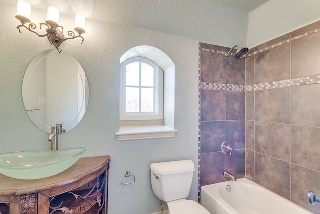 full bathroom featuring vanity, tiled shower / bath combo, and toilet