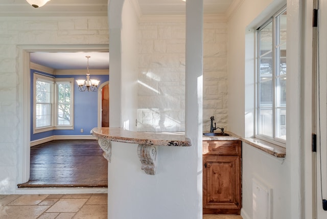 kitchen with sink, an inviting chandelier, a kitchen breakfast bar, crown molding, and pendant lighting