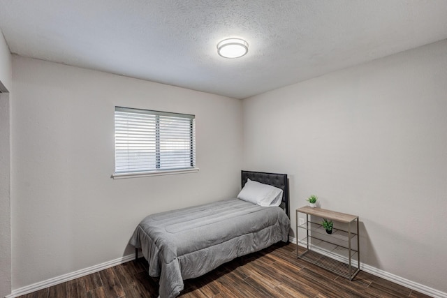 bedroom with a textured ceiling and dark hardwood / wood-style floors