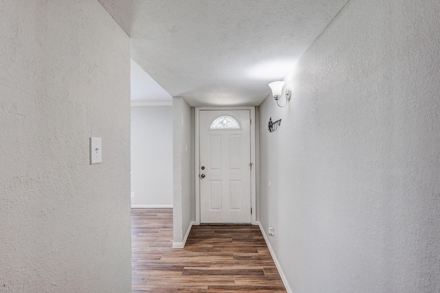 doorway to outside featuring dark hardwood / wood-style flooring, ornamental molding, and a textured ceiling