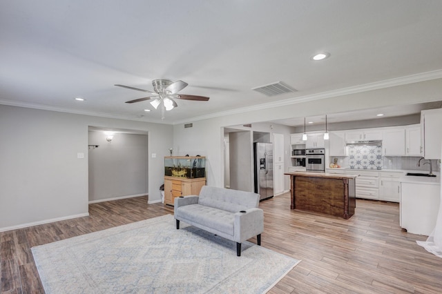 living area featuring light hardwood / wood-style flooring, ceiling fan, ornamental molding, and sink