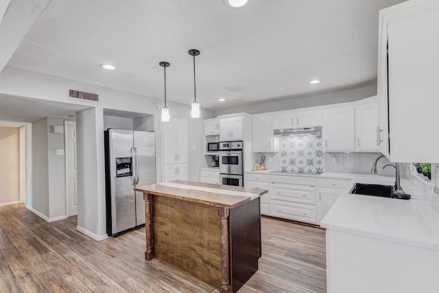 kitchen featuring a center island, sink, decorative backsplash, white cabinets, and appliances with stainless steel finishes