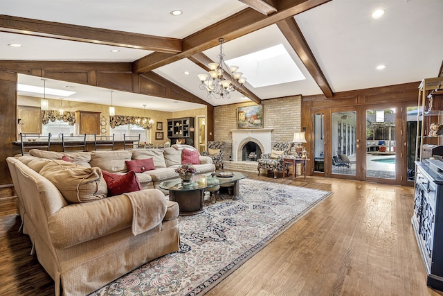 living room with a wealth of natural light, hardwood / wood-style floors, lofted ceiling with beams, and a notable chandelier