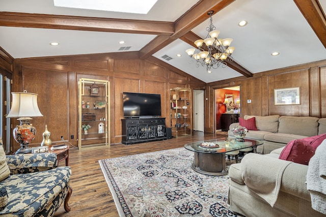 living room with hardwood / wood-style flooring, wood walls, lofted ceiling with skylight, and an inviting chandelier