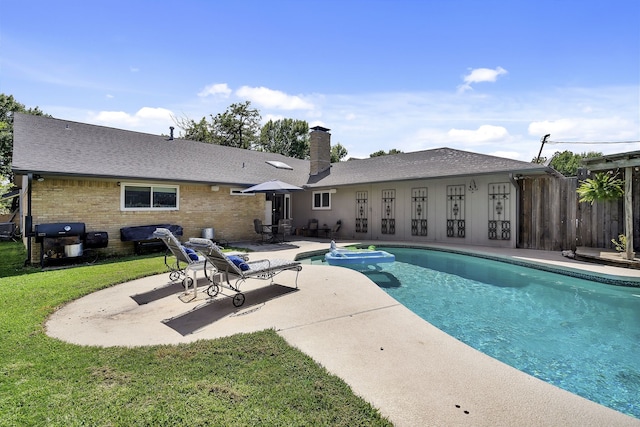 view of pool with area for grilling, a patio area, and a lawn