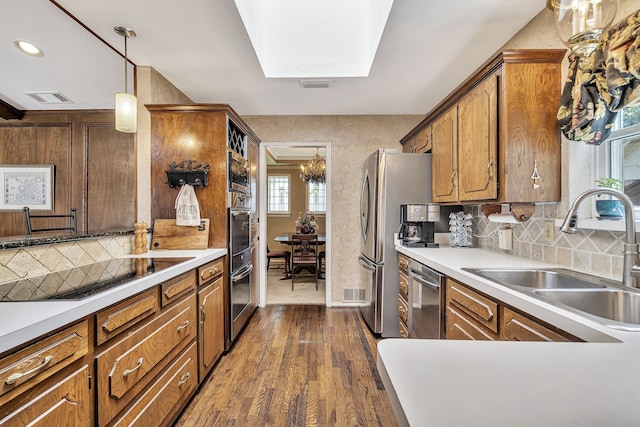 kitchen featuring a healthy amount of sunlight, sink, stainless steel appliances, and decorative light fixtures