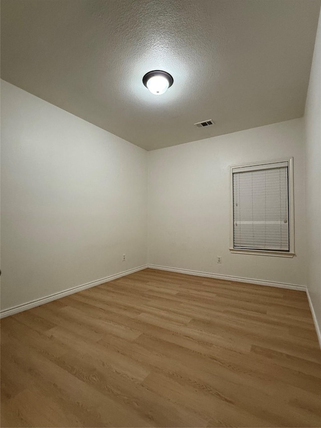 unfurnished room featuring a textured ceiling and light wood-type flooring