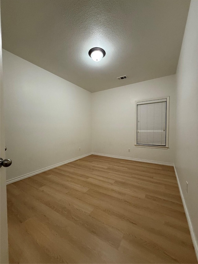 spare room featuring a textured ceiling and light wood-type flooring