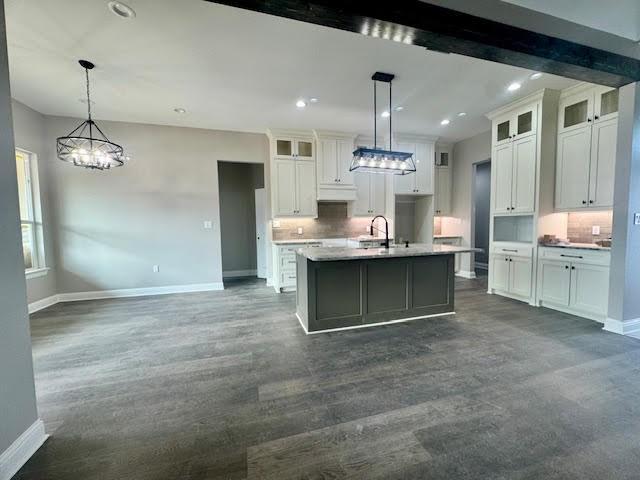 kitchen with a center island with sink, pendant lighting, white cabinetry, and sink