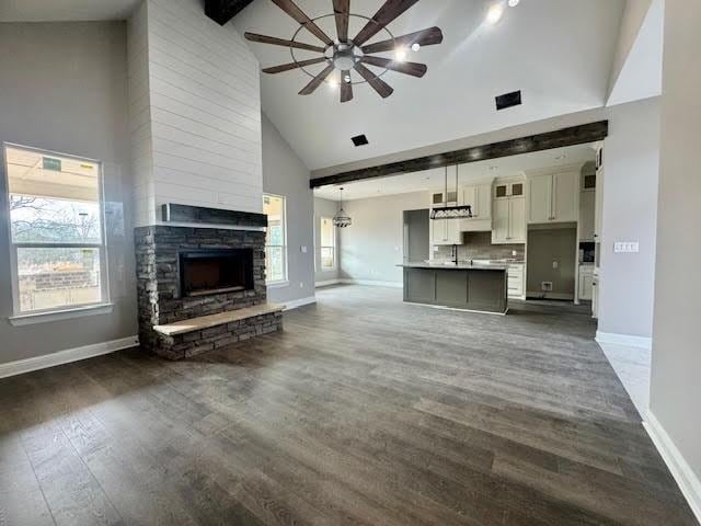 unfurnished living room with a fireplace, high vaulted ceiling, ceiling fan, and a healthy amount of sunlight