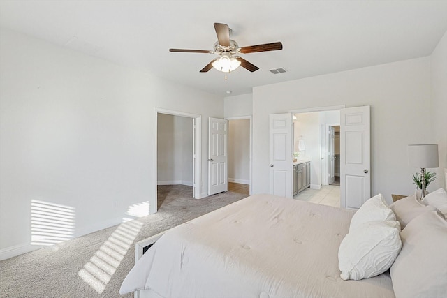 bedroom featuring ceiling fan, ensuite bathroom, light carpet, visible vents, and baseboards