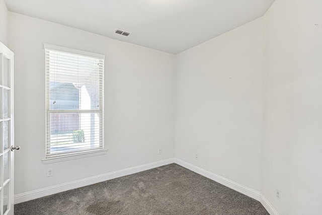 unfurnished room with carpet, visible vents, and baseboards