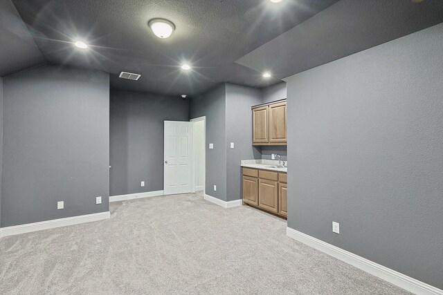 interior space with light colored carpet, lofted ceiling, and sink