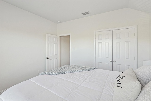 bedroom with vaulted ceiling, a closet, and visible vents