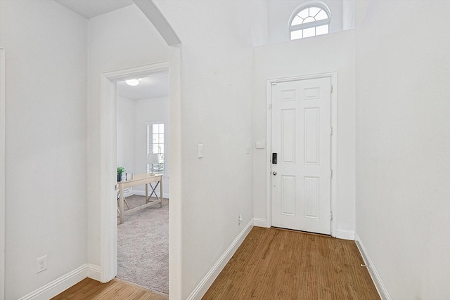 interior space featuring arched walkways, wood finished floors, and baseboards