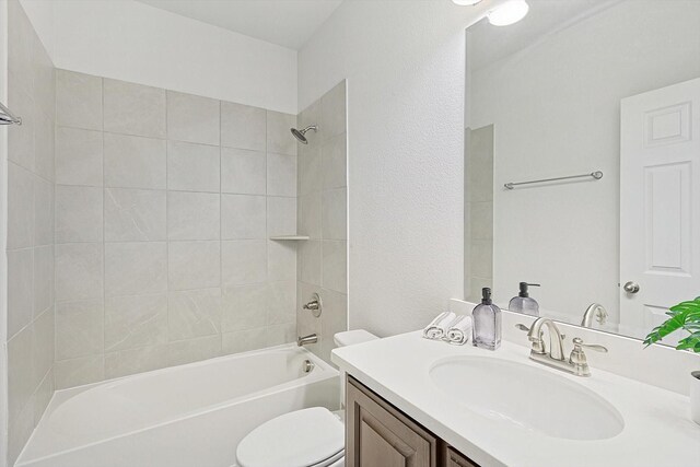 full bathroom with vanity, tiled shower / bath combo, and toilet