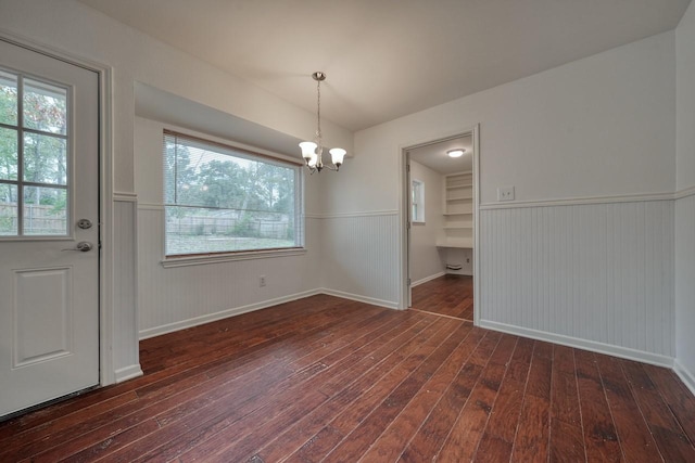 unfurnished dining area featuring dark hardwood / wood-style flooring, a chandelier, and plenty of natural light