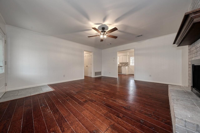 unfurnished living room featuring ceiling fan, dark wood-type flooring, and a brick fireplace