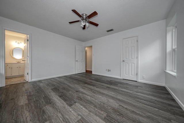 unfurnished bedroom featuring ceiling fan, a closet, dark wood-type flooring, and ensuite bath