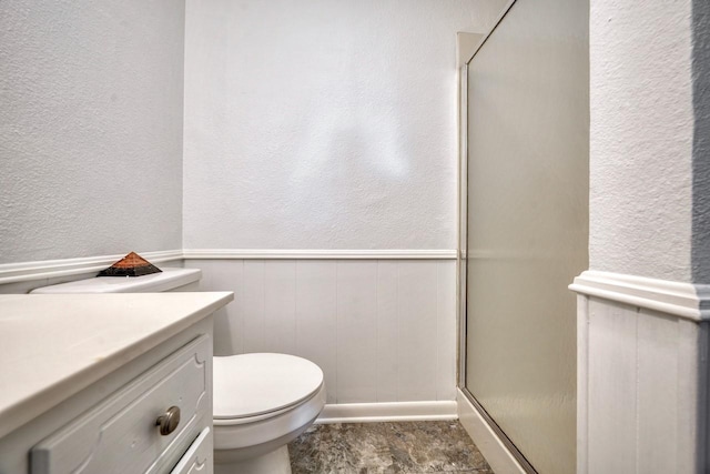 bathroom featuring vanity, toilet, and a shower with door